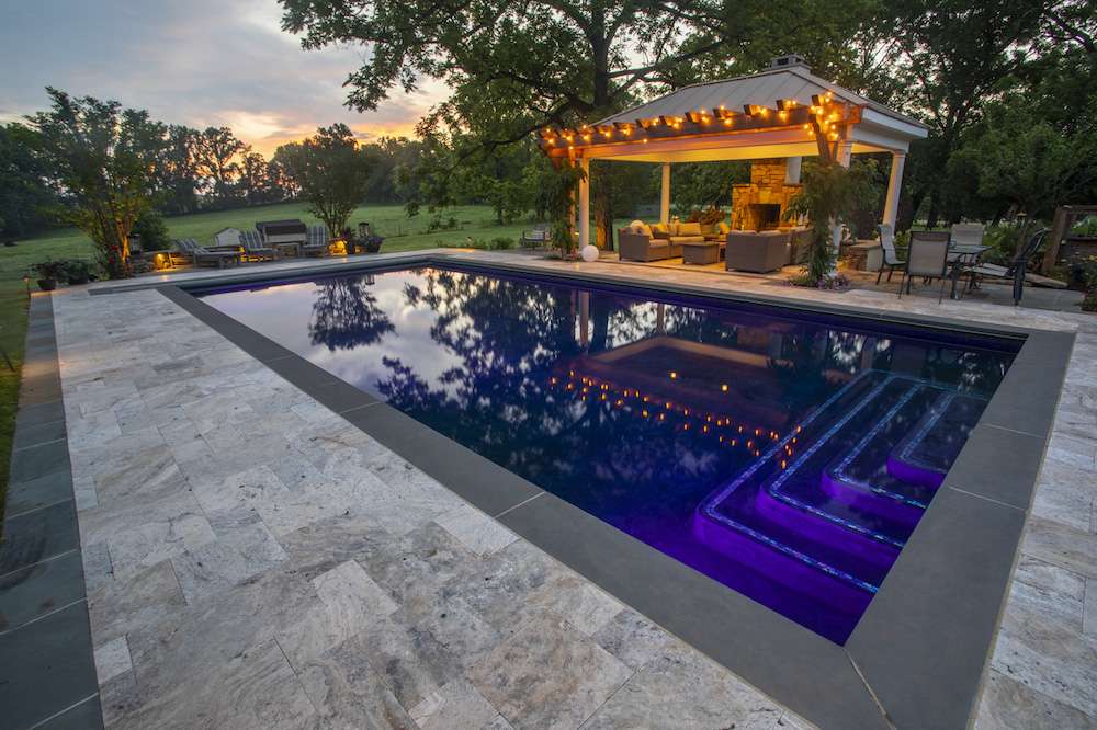 pool with patio deck and pavilion with fireplace