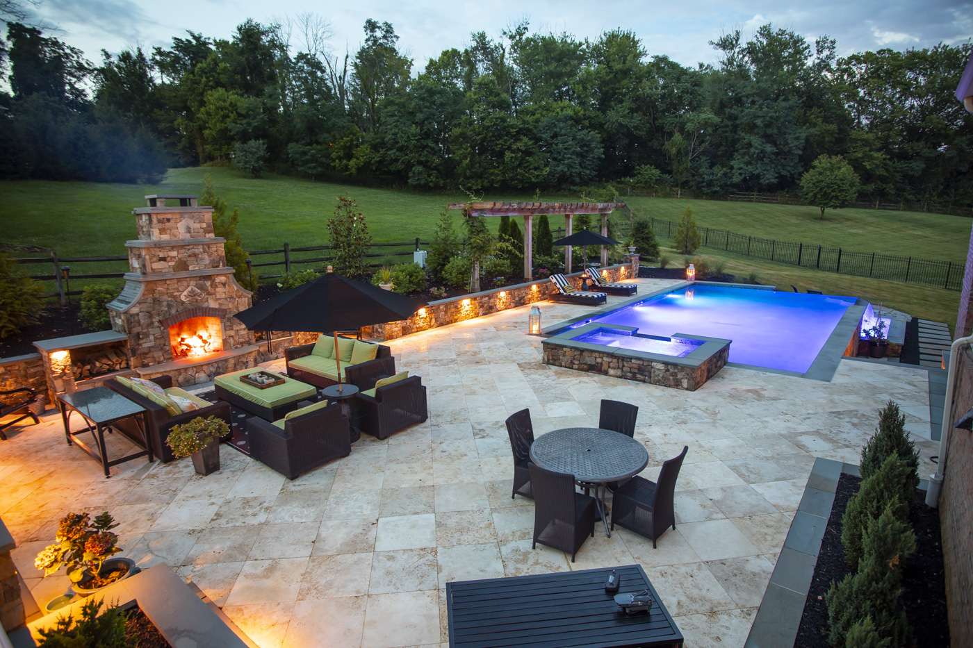 pool patio with natural stone, fire place, lighting, and hot tub
