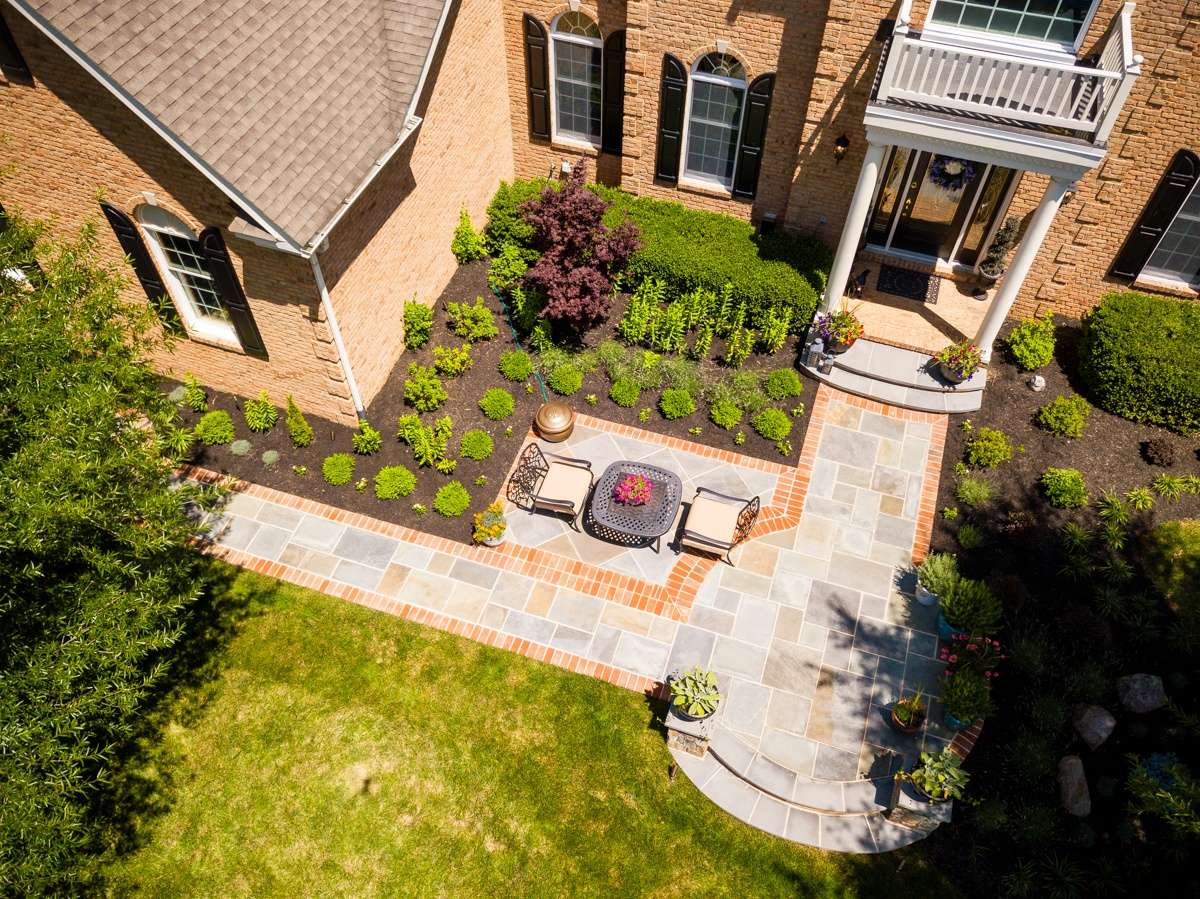 aerial photo of walkway with small patio area leading up to front entrance of home