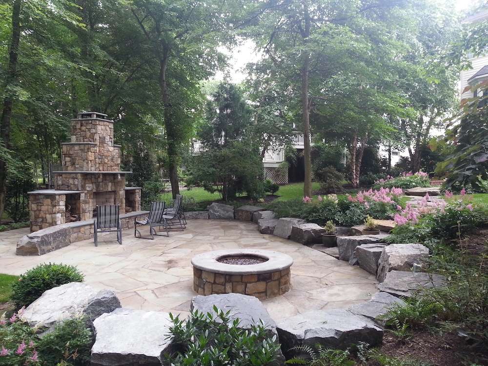 patio with outdoor fireplace and trees for privacy