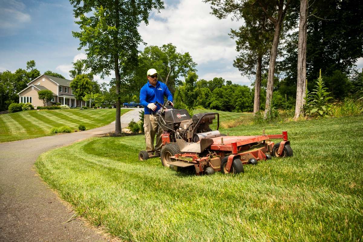 lawn care team mows lawn with ride on mower