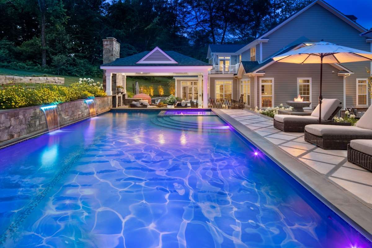 pool and hot tub with night lighting and patio