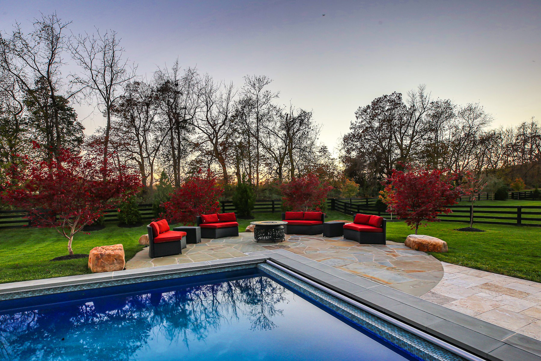 firepit near pool with red outdoor furniture