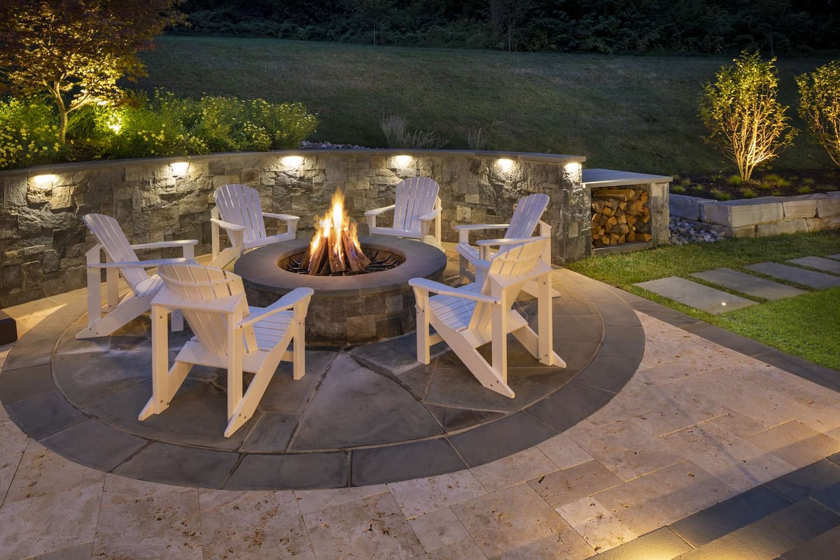 firepit on patio with wall and landscape lighting