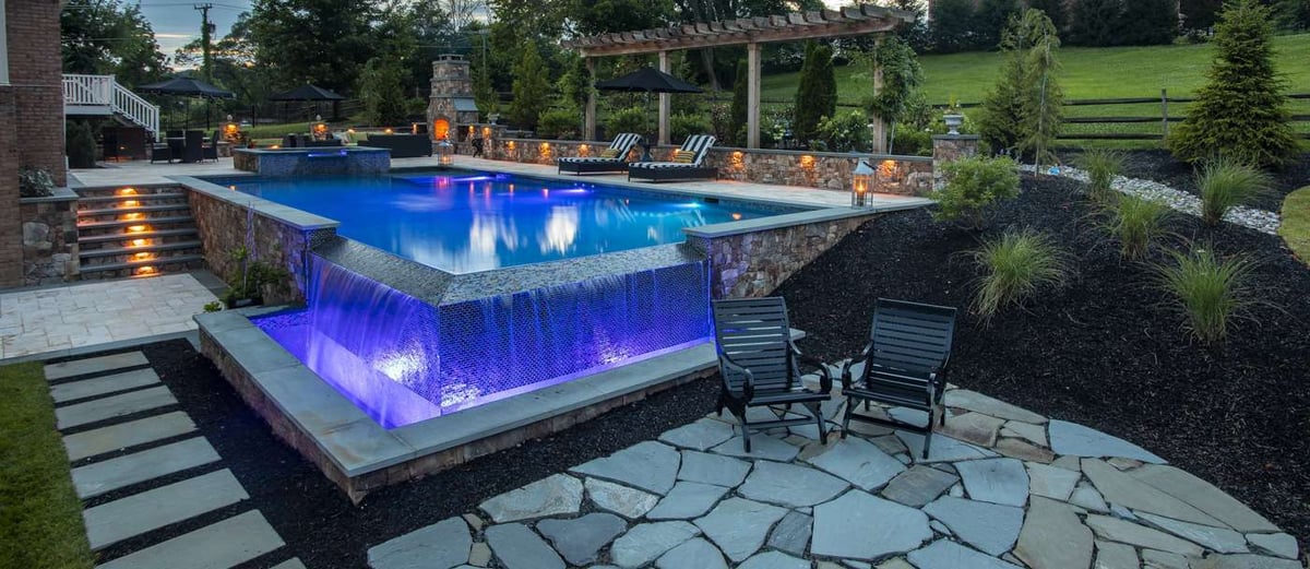 inground pool with lighting patio and outdoor fireplace
