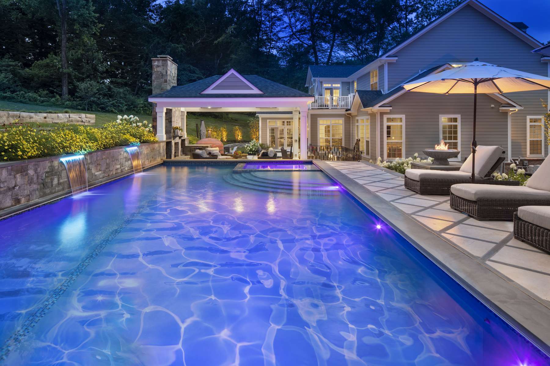 Pool with sheer descent waterfalls and travertine patio