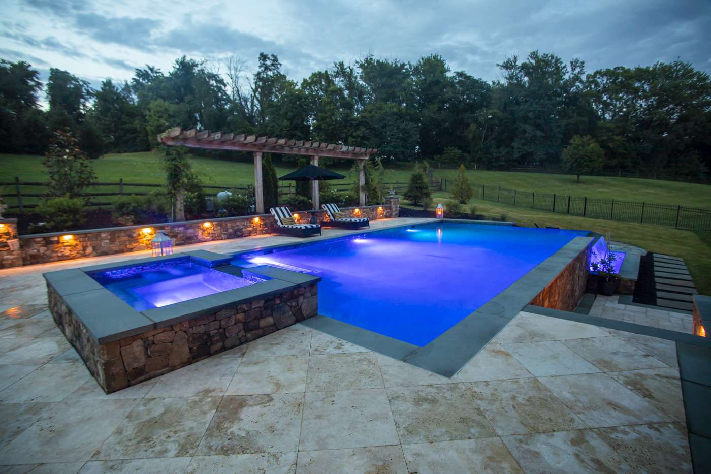 pool with lighting and nearby chairs and pergola