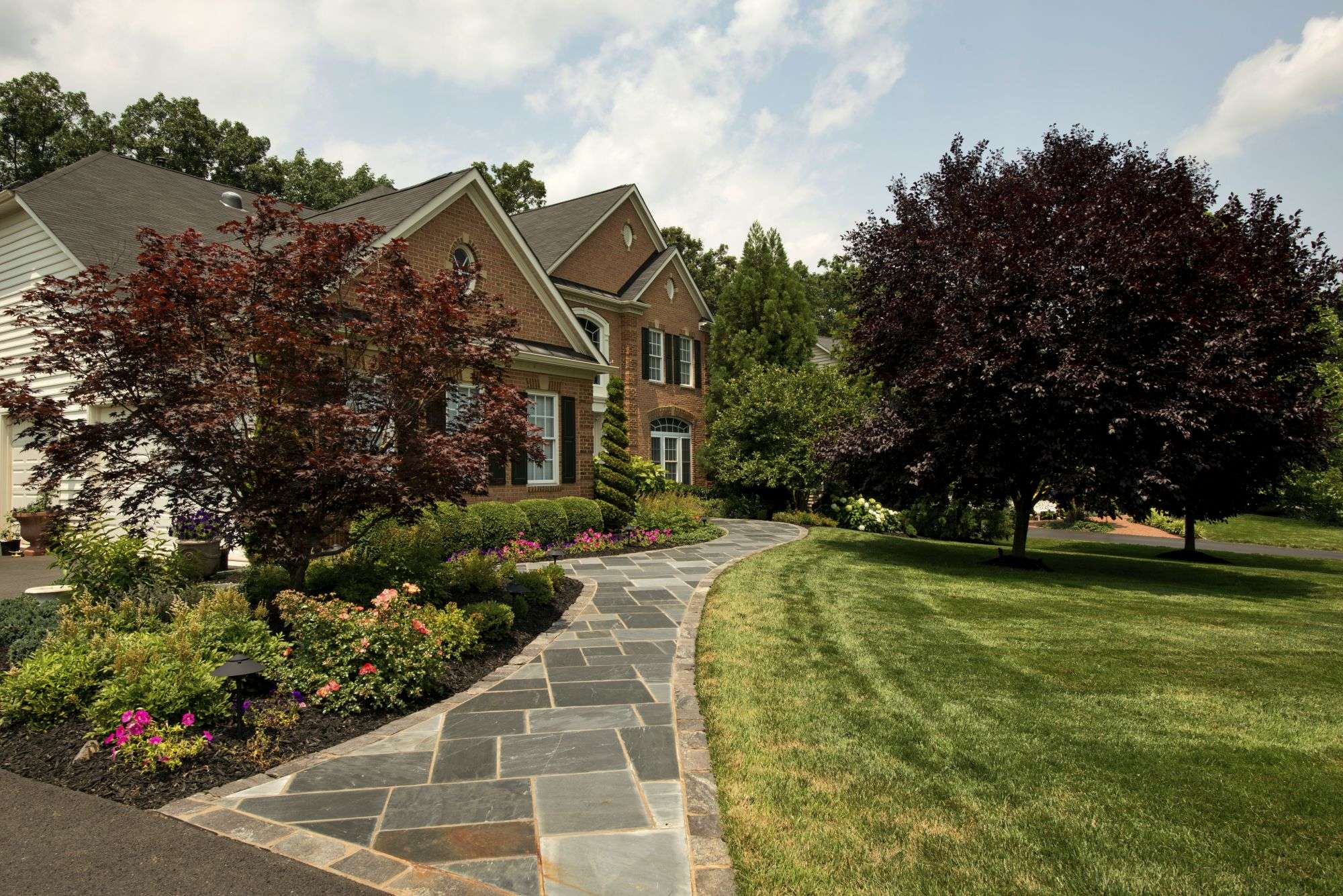 Stone walkway design and landscaping in front of house