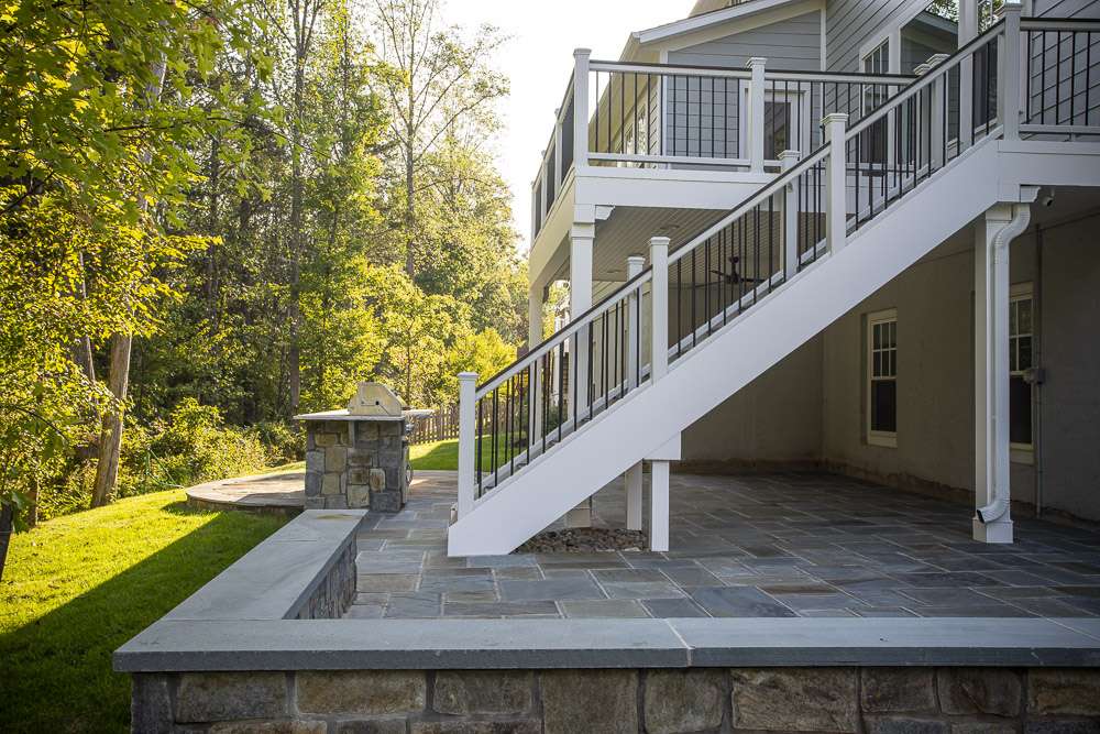 deck on back of home with paver patio and seat wall